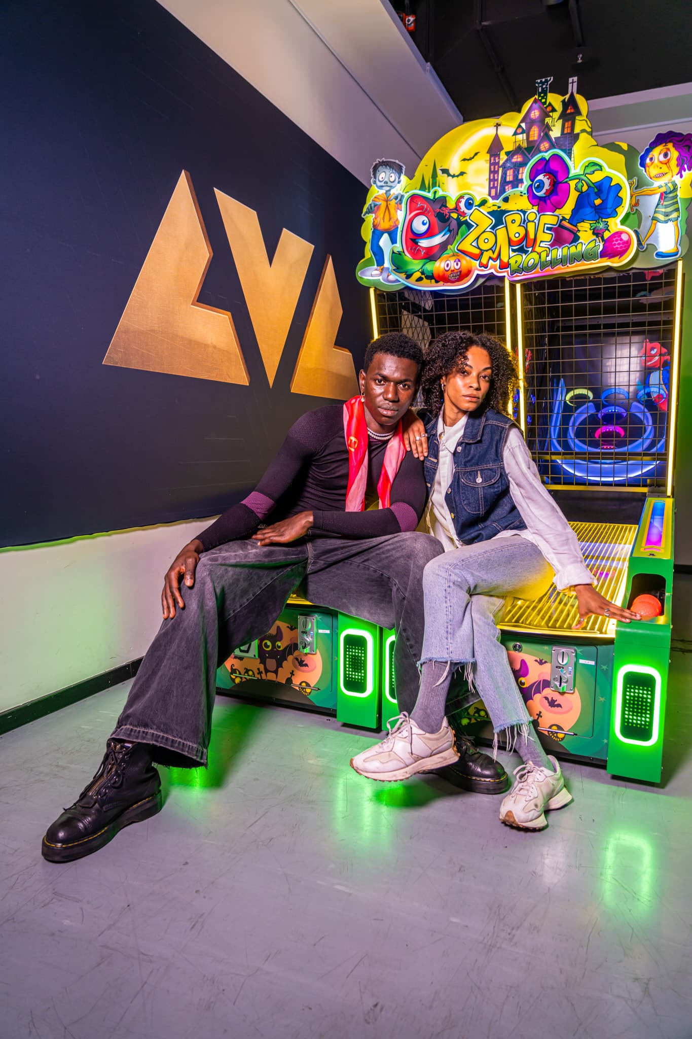 Guests posing by the LVL sign next to an arcade cabinet