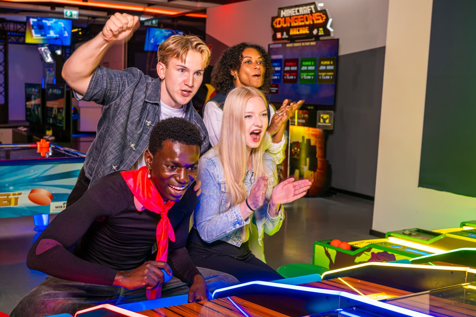 A group of friends cheering at the air hockey table