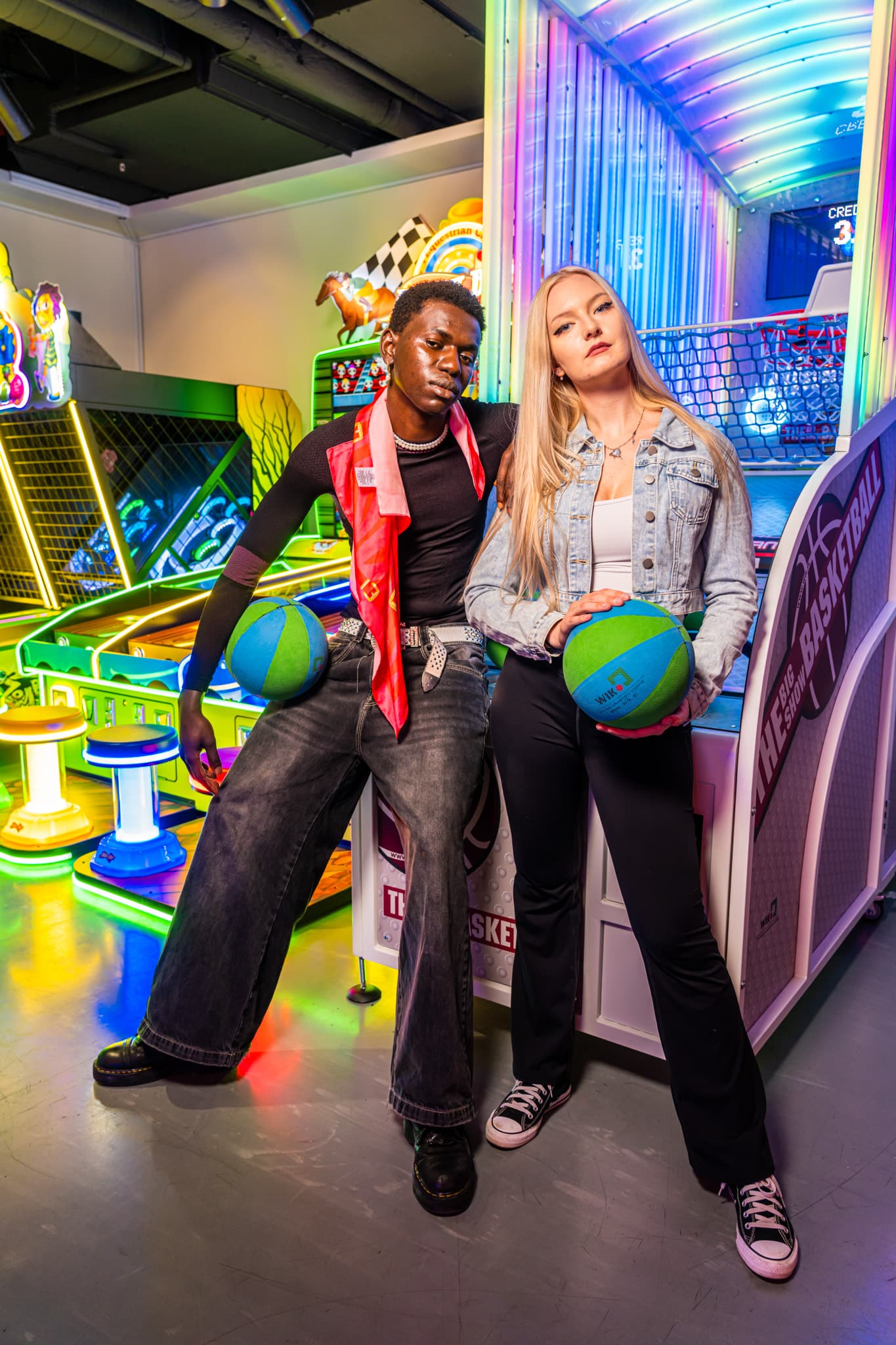 Two friends posing with balls at the arcade basketball game
