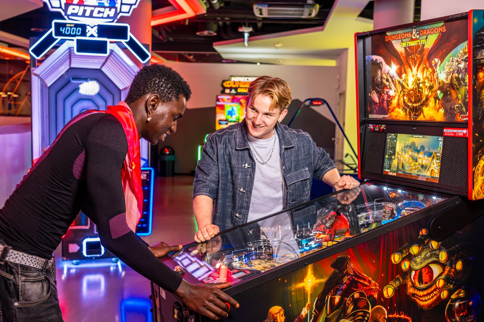 Two friends laughing together over a pinball machine