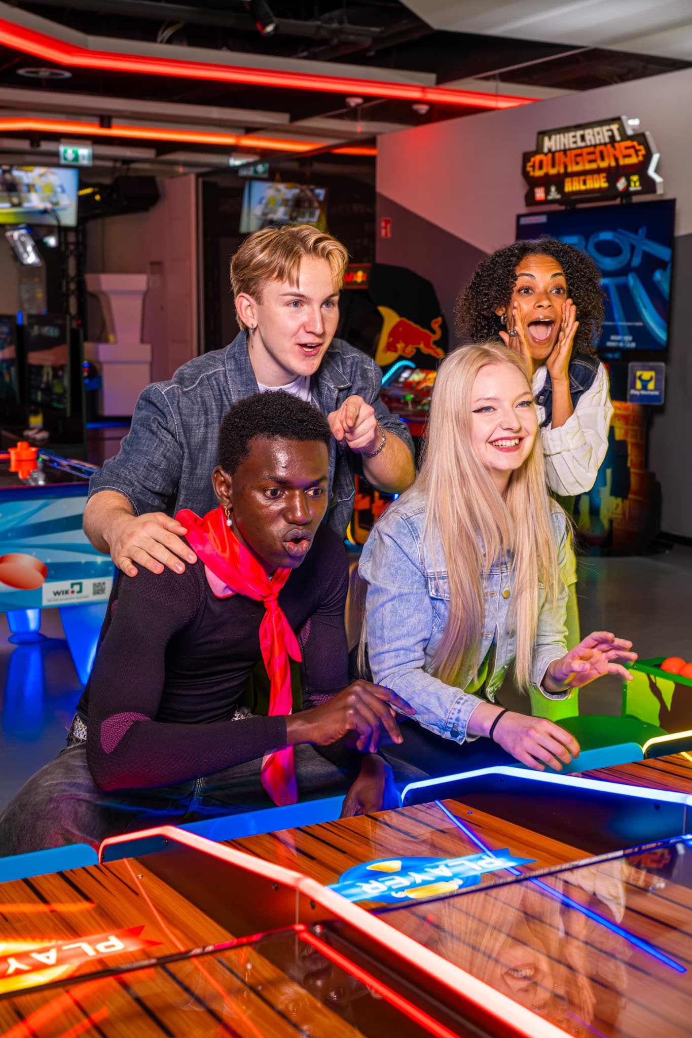 A group of friends cheering excitedly around an air hockey table