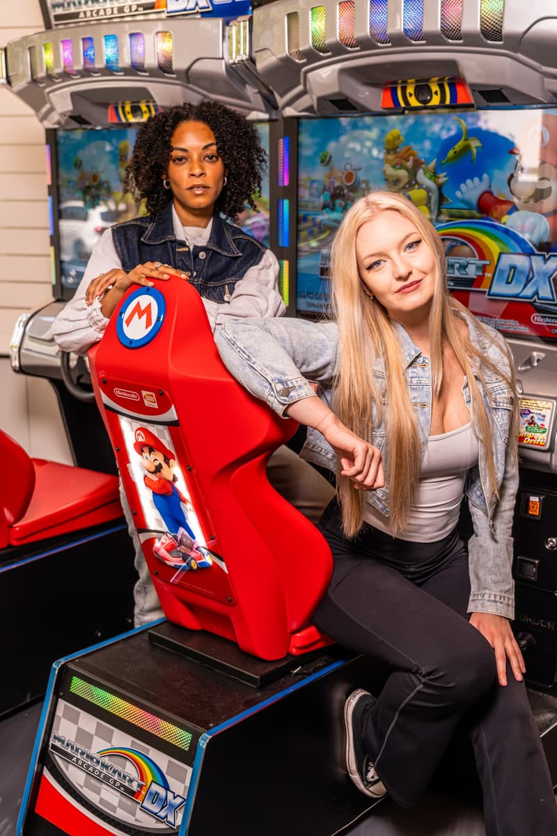 Two friends posing together at a Mario Kart racing cabinet
